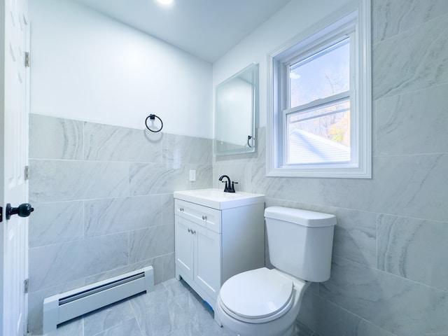 bathroom with vanity, toilet, baseboard heating, and tile walls