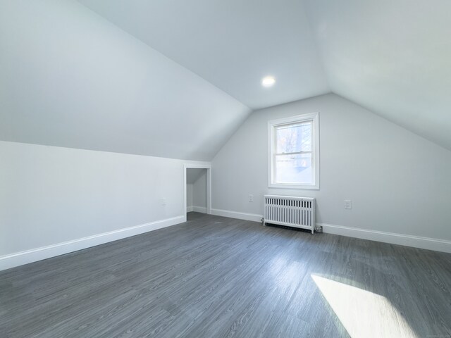 additional living space featuring dark hardwood / wood-style flooring, radiator heating unit, and lofted ceiling