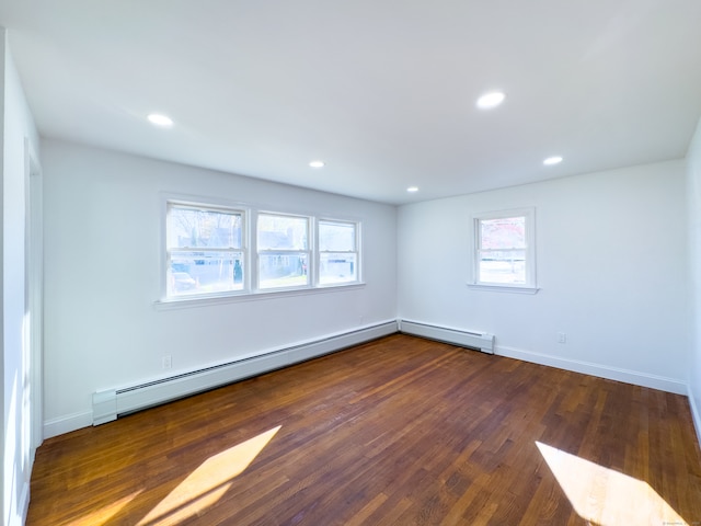 spare room with plenty of natural light, dark hardwood / wood-style floors, and a baseboard heating unit