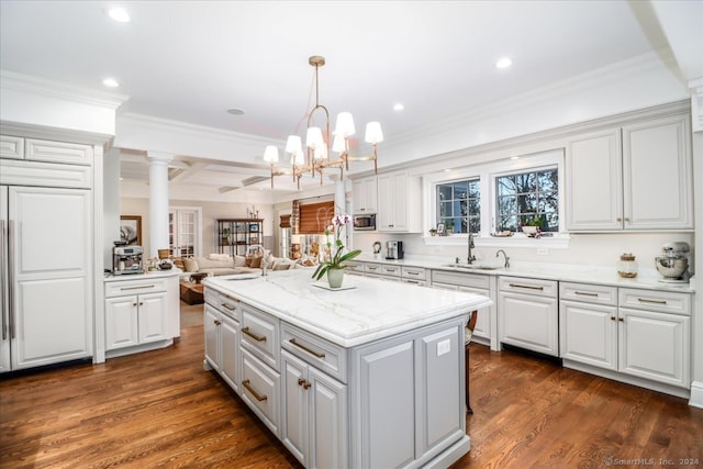 kitchen with decorative columns, sink, white cabinetry, dark hardwood / wood-style floors, and a kitchen island