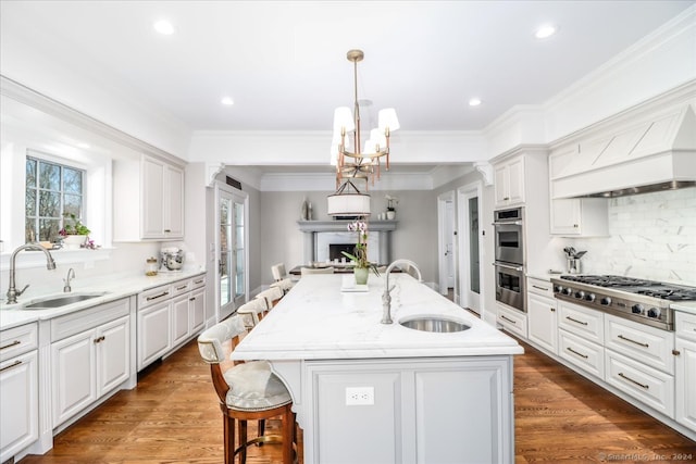 kitchen featuring dark hardwood / wood-style floors, white cabinetry, a kitchen island with sink, and sink