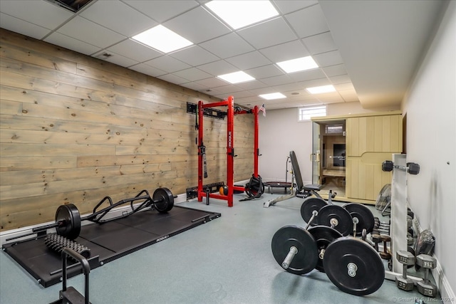 exercise area with a drop ceiling and wooden walls