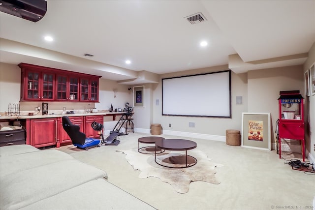 cinema room with bar area and light colored carpet