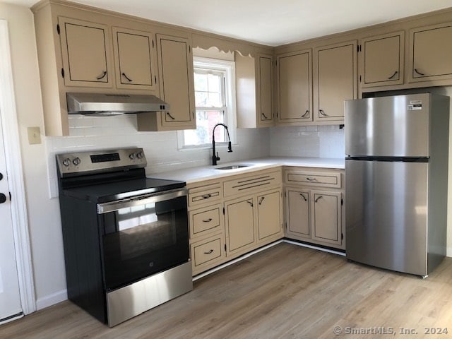 kitchen featuring tasteful backsplash, sink, light hardwood / wood-style floors, and appliances with stainless steel finishes