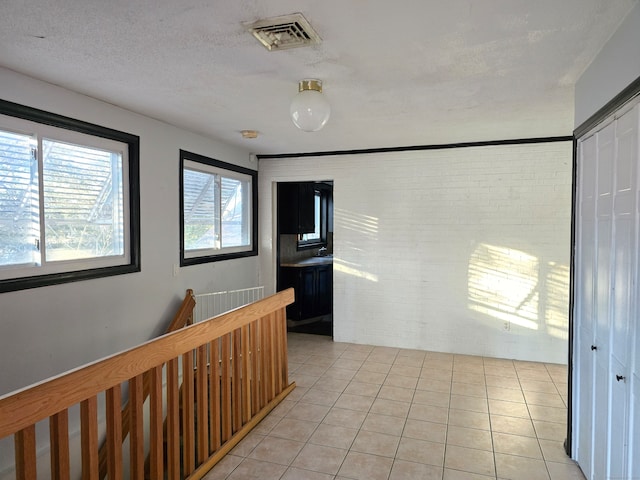 hallway with light tile patterned floors and brick wall