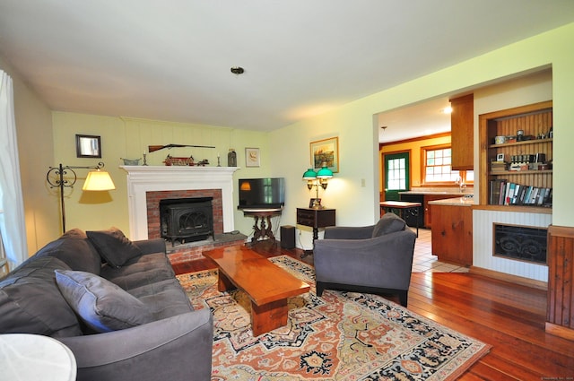 living room featuring a fireplace, built in shelves, and hardwood / wood-style flooring