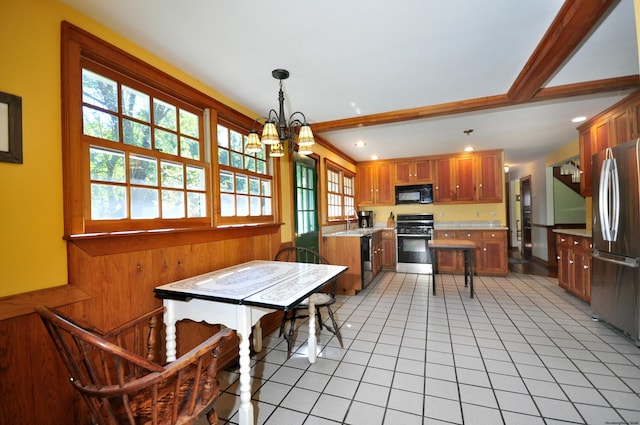 kitchen with wood walls, a chandelier, decorative light fixtures, light tile patterned floors, and black appliances