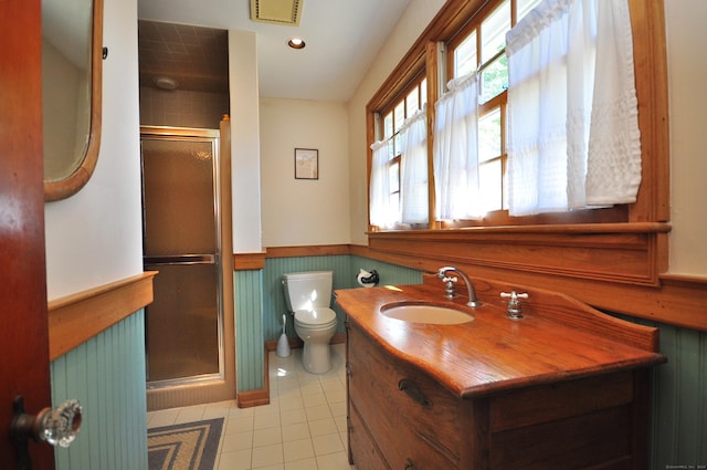 bathroom featuring tile patterned flooring, vanity, toilet, and a shower with door