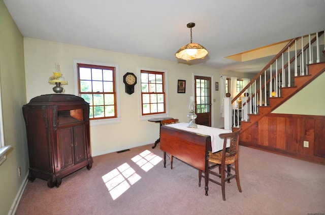 carpeted dining room featuring wood walls