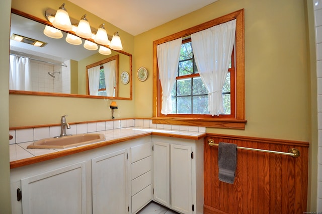 kitchen with white cabinetry, tile counters, and sink