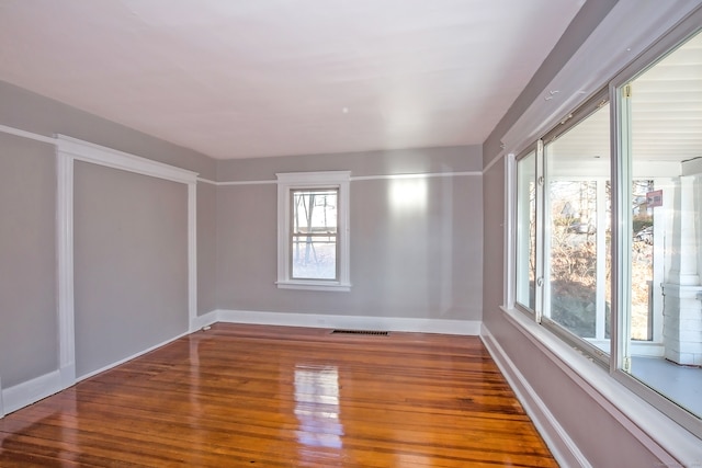 empty room featuring plenty of natural light and dark wood-type flooring