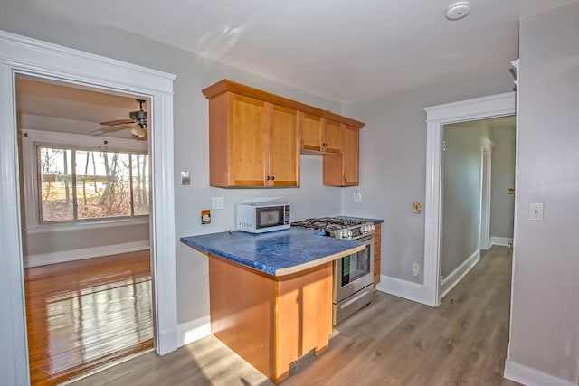 kitchen with ceiling fan, light hardwood / wood-style flooring, and stainless steel range with gas stovetop