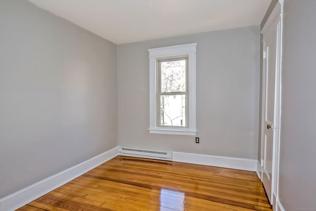 empty room with wood-type flooring and a baseboard radiator