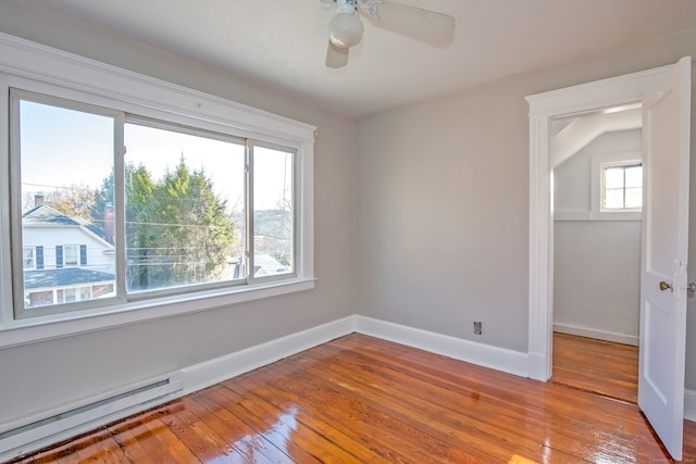 empty room with ceiling fan, vaulted ceiling, baseboard heating, and light hardwood / wood-style flooring