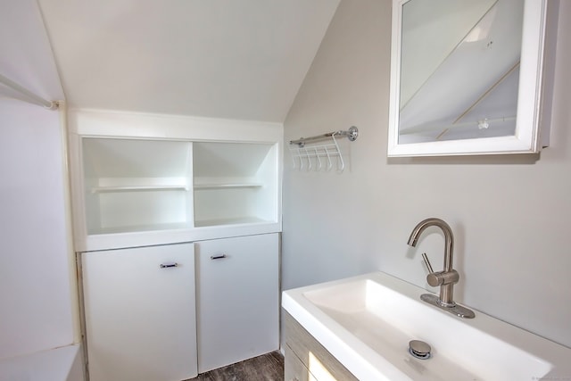 bathroom with hardwood / wood-style floors, vanity, and vaulted ceiling