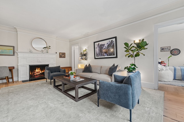 living room featuring wood-type flooring, crown molding, and a brick fireplace