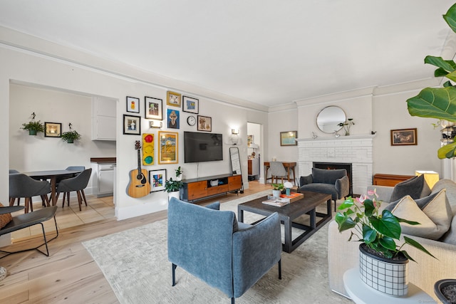 living room with a fireplace, light wood-type flooring, and ornamental molding