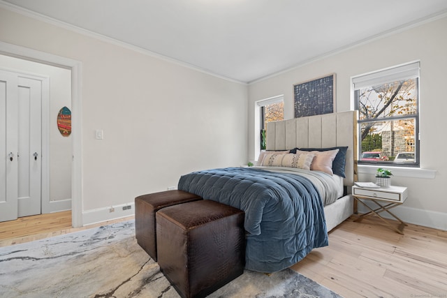 bedroom featuring light hardwood / wood-style floors, multiple windows, and ornamental molding