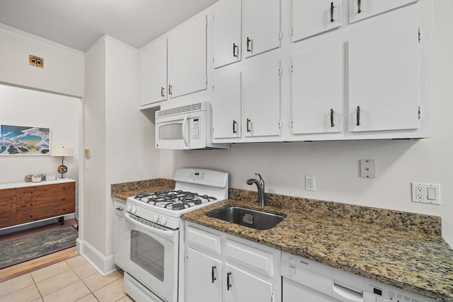 kitchen featuring white appliances, dark stone counters, white cabinets, sink, and light tile patterned flooring