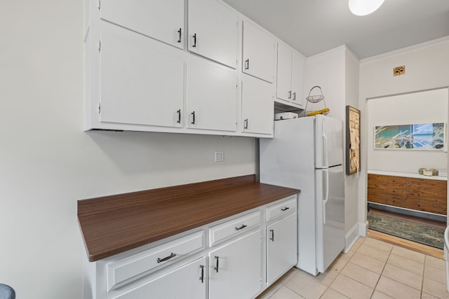 kitchen with white cabinets, white fridge, and light tile patterned flooring