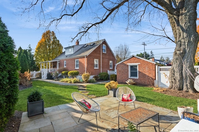 back of property with a lawn and a patio