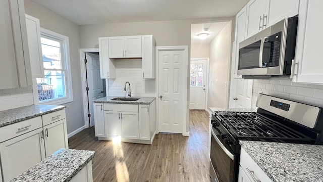 kitchen featuring wood-type flooring, sink, white cabinetry, and stainless steel appliances