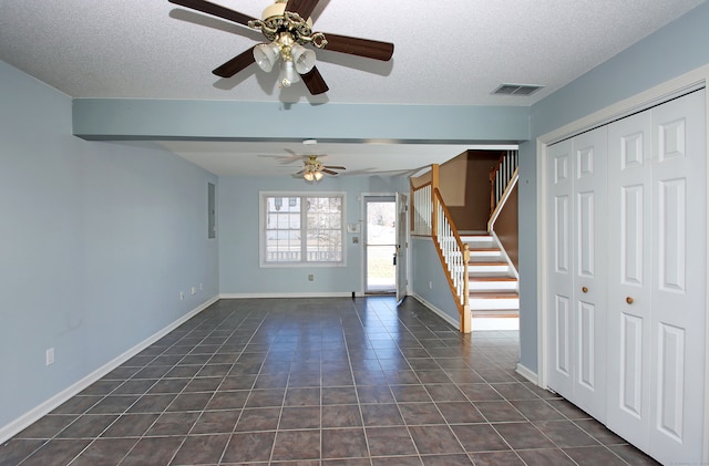 unfurnished room featuring a textured ceiling, dark tile patterned flooring, and ceiling fan