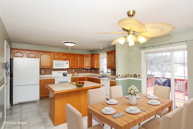 kitchen featuring sink, a center island, tasteful backsplash, white appliances, and light tile patterned floors