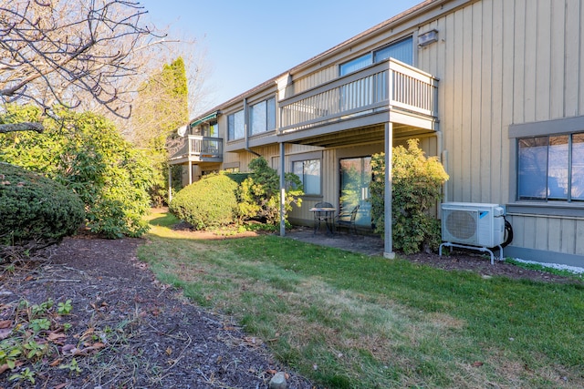 back of property with a balcony, a yard, and ac unit