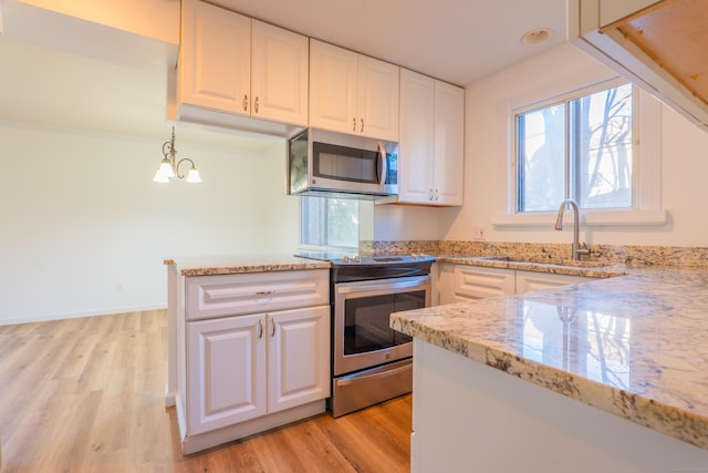 kitchen with light wood finished floors, appliances with stainless steel finishes, light stone countertops, and a sink