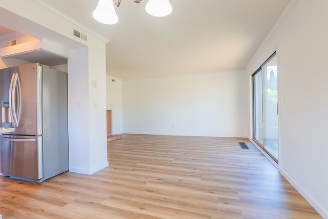 empty room featuring visible vents, light wood-style flooring, baseboards, and ornamental molding