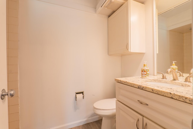 bathroom featuring toilet, vanity, baseboards, and wood finished floors