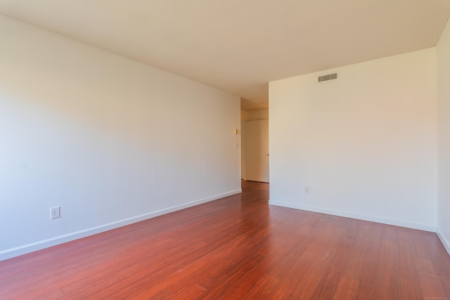 spare room featuring visible vents, baseboards, and wood finished floors