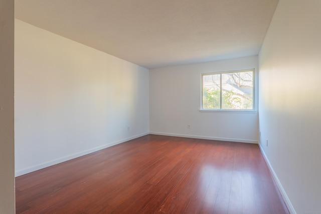 empty room featuring baseboards and dark wood-style flooring