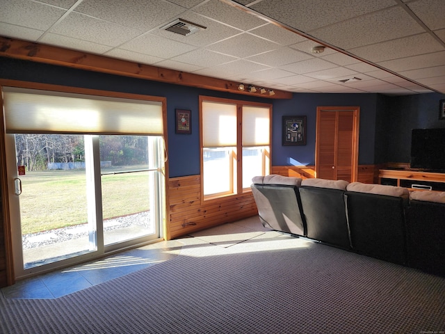 interior space featuring carpet floors, a drop ceiling, and wooden walls