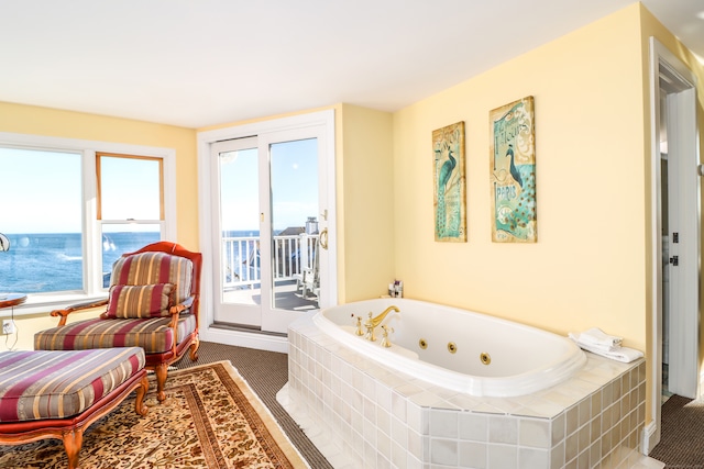 bathroom with a relaxing tiled tub and a water view