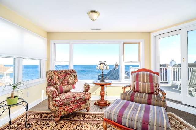 sitting room featuring carpet, a water view, and a healthy amount of sunlight