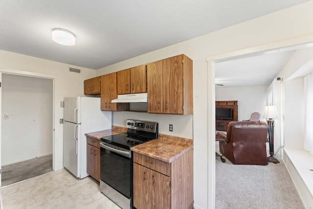 kitchen with a textured ceiling, light colored carpet, stainless steel range with electric stovetop, and white refrigerator