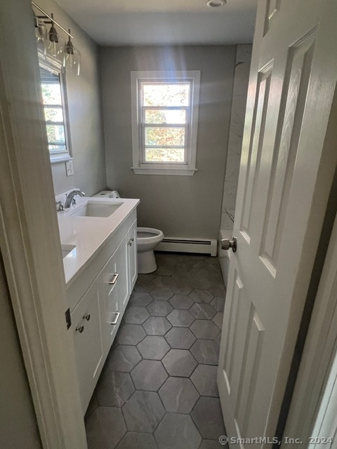 bathroom with tile patterned flooring, toilet, vanity, and a baseboard heating unit