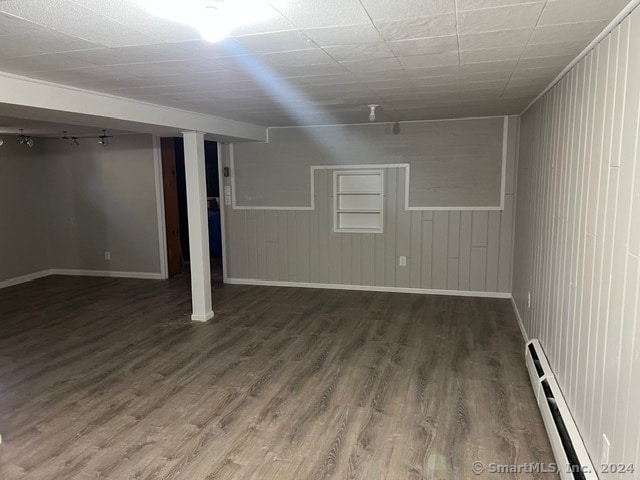 basement featuring dark hardwood / wood-style flooring and a baseboard heating unit