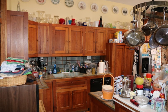 kitchen with a sink, tile countertops, brown cabinetry, decorative backsplash, and black dishwasher