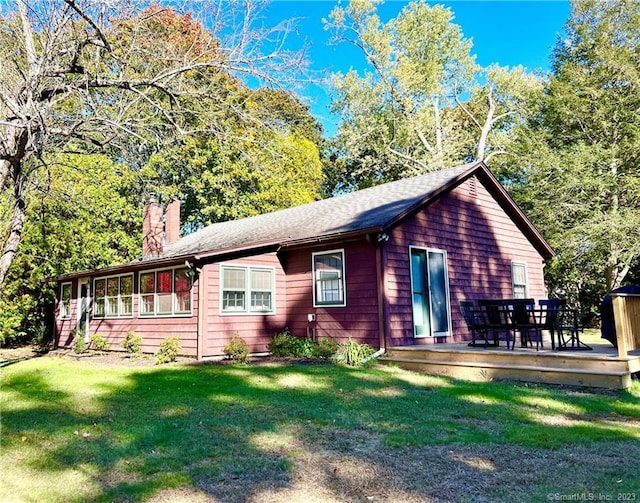 view of front facade with a wooden deck and a front lawn