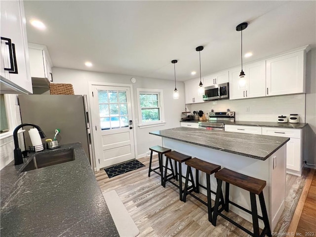 kitchen featuring white cabinetry, sink, light hardwood / wood-style flooring, and appliances with stainless steel finishes