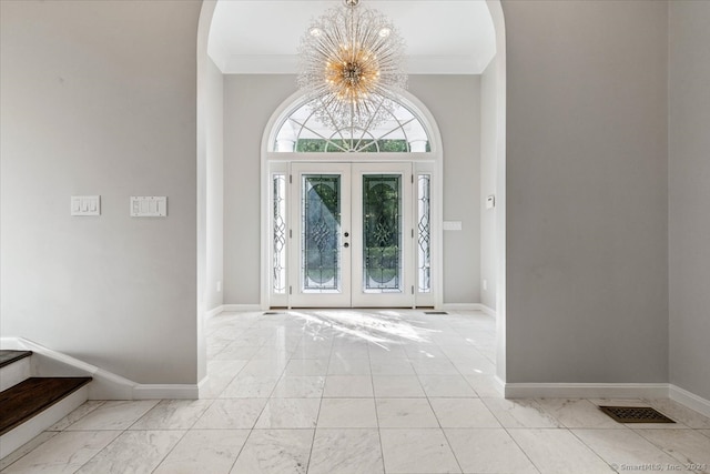 foyer entrance featuring an inviting chandelier, ornamental molding, and french doors