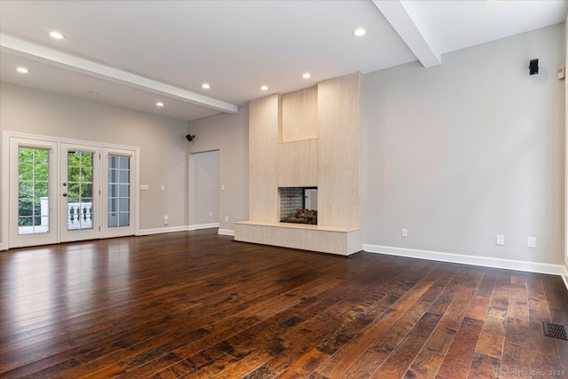 unfurnished living room featuring beam ceiling, a large fireplace, and dark hardwood / wood-style flooring