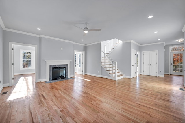 unfurnished living room with light wood-type flooring, a wealth of natural light, and crown molding