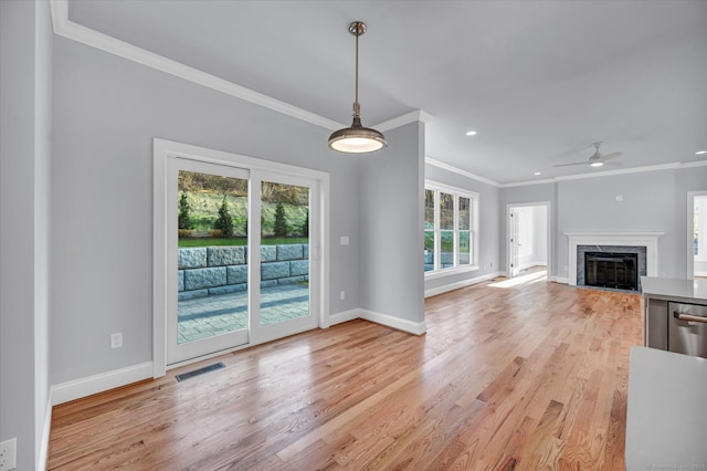 unfurnished living room featuring a fireplace, light hardwood / wood-style floors, ceiling fan, and a healthy amount of sunlight