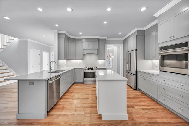 kitchen with appliances with stainless steel finishes, light hardwood / wood-style flooring, a kitchen island, and sink