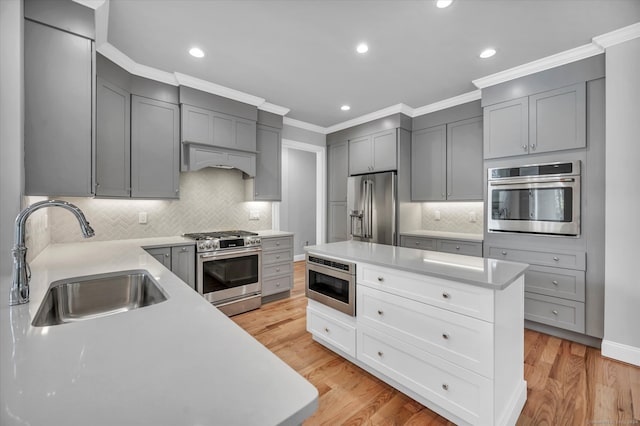 kitchen featuring a kitchen island, sink, appliances with stainless steel finishes, and light hardwood / wood-style flooring