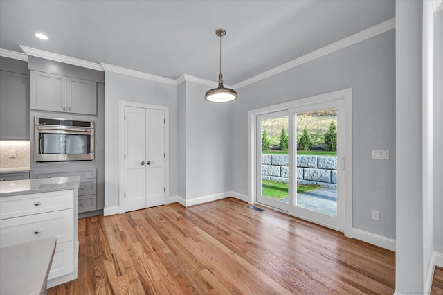 kitchen featuring pendant lighting, oven, light wood-type flooring, ornamental molding, and tasteful backsplash